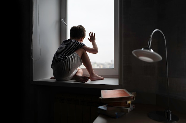 Chłopiec siedzi sam na oknie