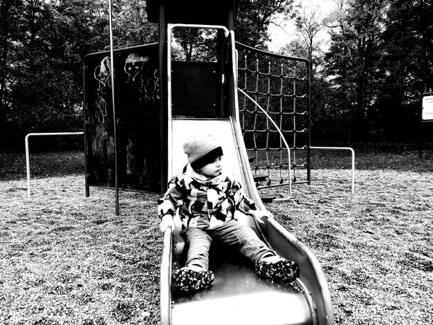 Zdjęcie chłopiec ślizgający się na zjeżdżalni na placu zabaw