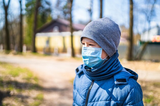 Chłopiec spacerujący na zewnątrz z maską na twarz dla ochrony Chłopiec szkolny oddychający przez maskę medyczną Epidemia koronowirusa COVID19 i identyfikacja koronawirusa Pandemia