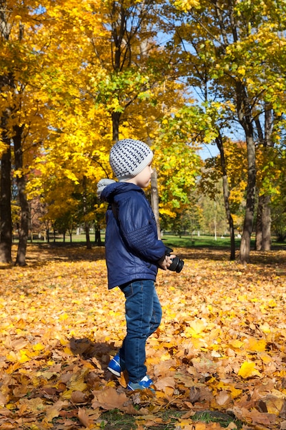Chłopiec spacerujący po parku, który fotografuje otoczenie, specyfikę jesiennej przyrody,