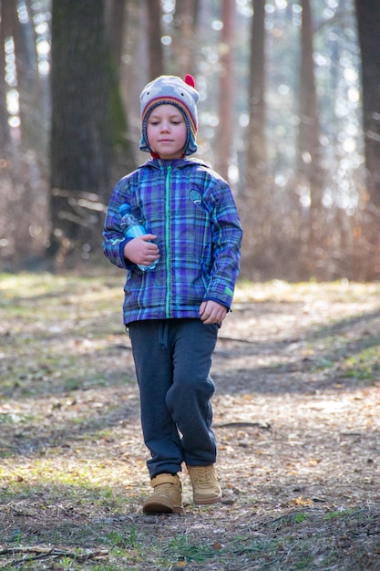 Chłopiec spędza szczęśliwy czas na świeżym powietrzu w lesie ciesząc się jesienną przyrodą