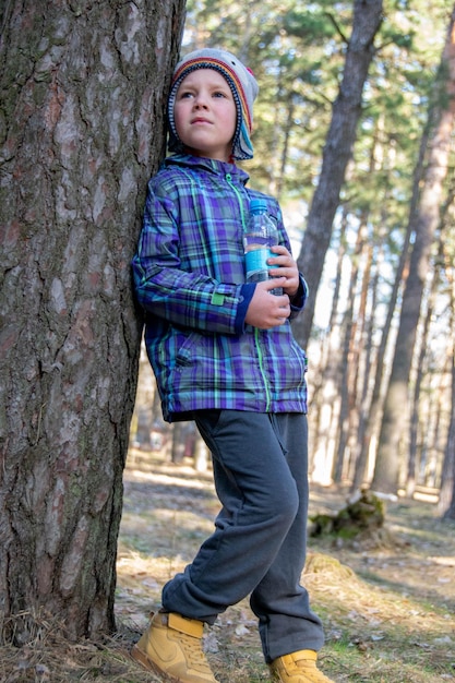 Chłopiec spędza szczęśliwy czas na świeżym powietrzu w lesie ciesząc się jesienną przyrodą