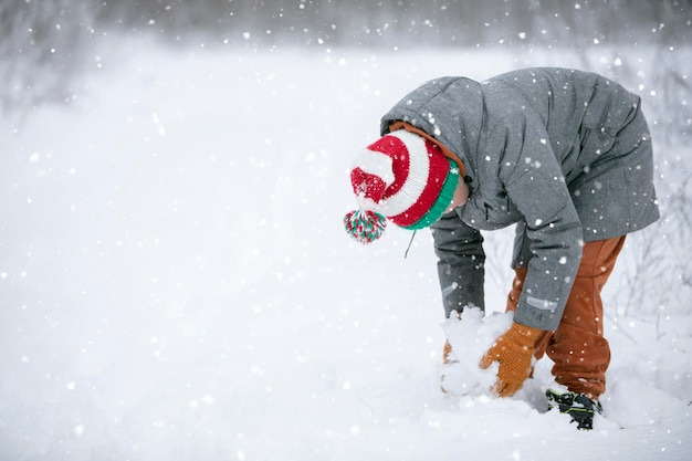 Chłopiec sprawia, że snowball na śnieżnym polu Dziecko bawi się zimą ze śniegiem