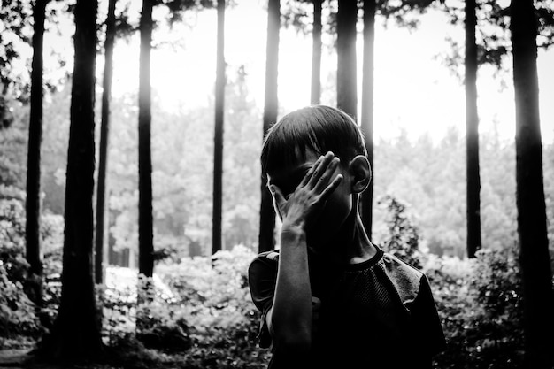 Zdjęcie chłopiec stojący w lesie