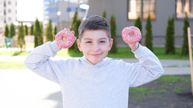 Chłopiec trzyma sproszkowane pączki pod oczy up