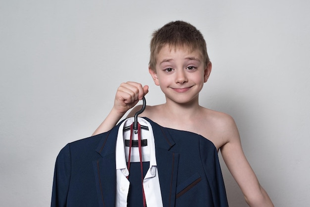 Chłopiec trzyma w rękach garnitur mundurek szkolny Szczęśliwy chłopiec idzie do szkoły
