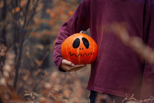 Chłopiec trzyma w rękach straszną dyni Halloween