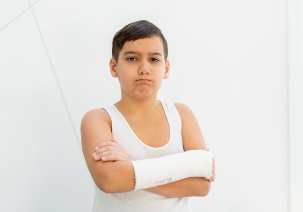 Chłopiec trzyma złamaną rękę w gipsie, ramię gipsowe, wypadek w domu, uraz, koncepcja urazu. Wysokiej jakości zdjęcie