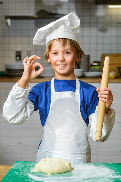 Chłopiec ubrany jak kucharz przygotowuje ciasto