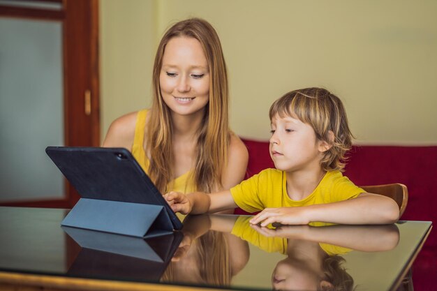 Chłopiec uczący się online w domu za pomocą tabletu Mama pomaga mu się uczyć Uczenie się podczas kwarantanny Globalny wirus pandemiczny covid19