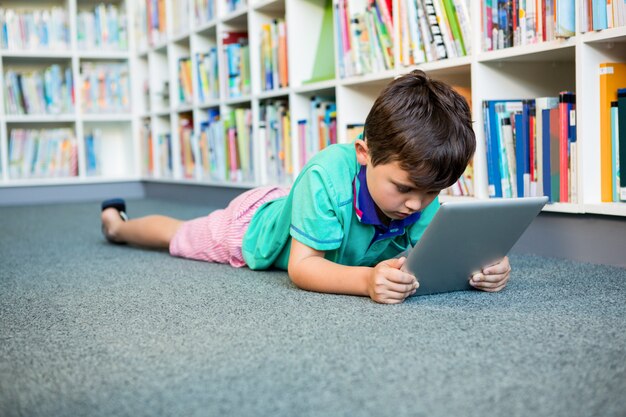 Chłopiec używa cyfrową pastylkę w szkolnej bibliotece