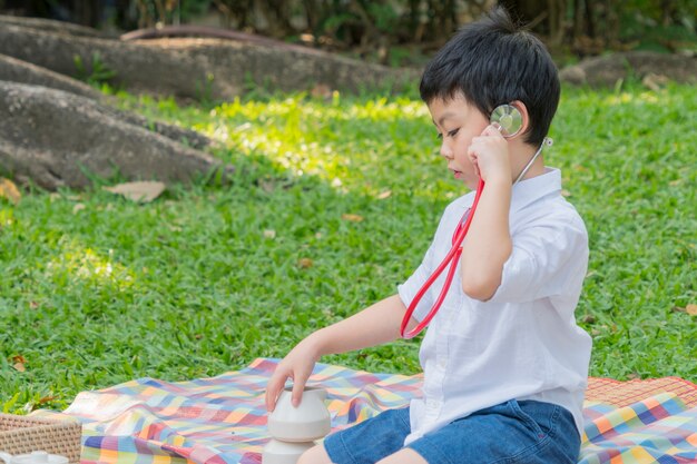 chłopiec używa stetoskopy i czuje się szczęśliwy w parku ogrodowym