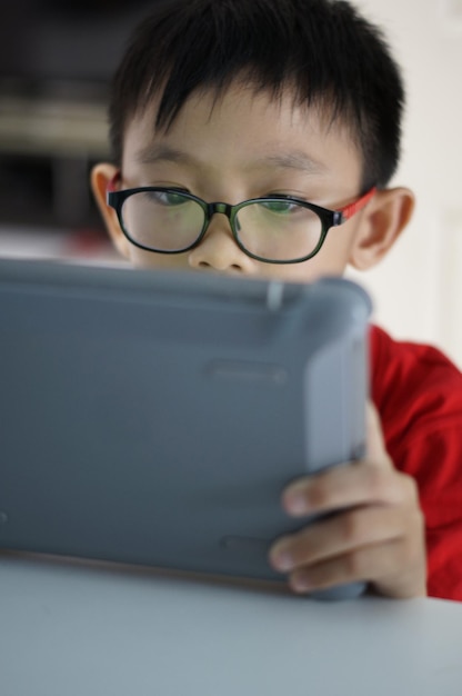 Chłopiec używający tabletu cyfrowego siedząc przy stole w domu