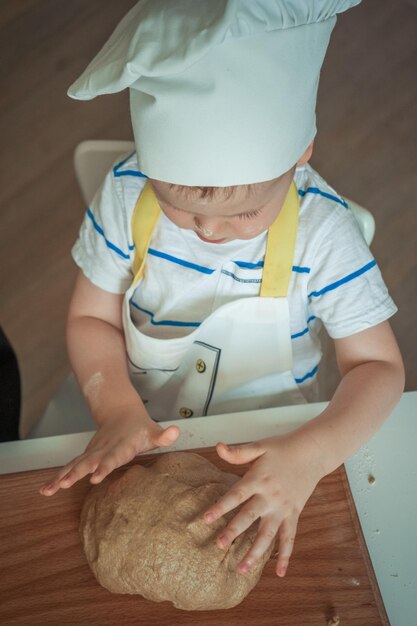 Chłopiec w białym kapeluszu robi ciasto.