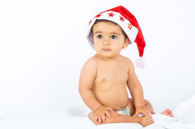 Chłopiec w czerwonej świątecznej czapce na białym tle, kopia przestrzeń, portret dziecka w czapce Mikołaja