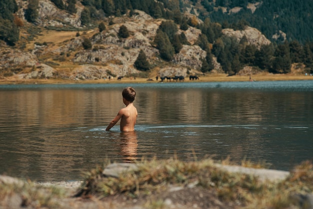 Chłopiec w jeziorze z górami w tle