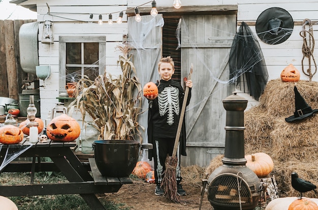 Chłopiec w kostiumie szkieleta na ganku domu udekorowanego z okazji przyjęcia Halloween Halloween