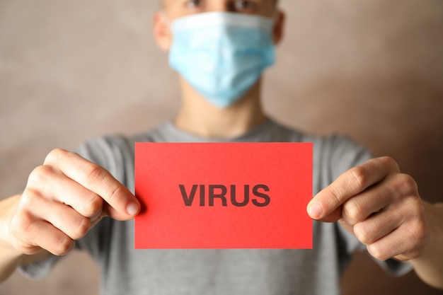 Zdjęcie chłopiec w masce ochronnej trzyma napis coronavirus na brązowym tle. pojęcie opieki zdrowotnej i medycznej