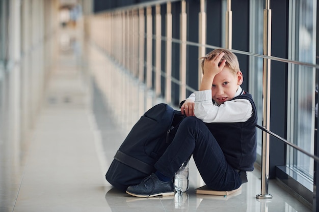 Chłopiec w mundurze siedzi sam ze smutkiem w szkole Poczęcie molestowania