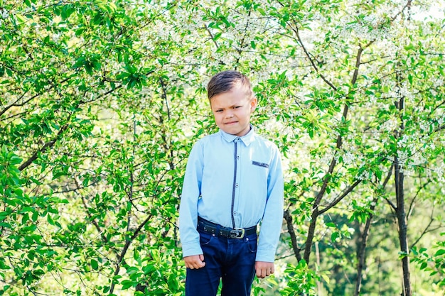 Chłopiec w niebieskiej koszuli na tle kwitnących drzew