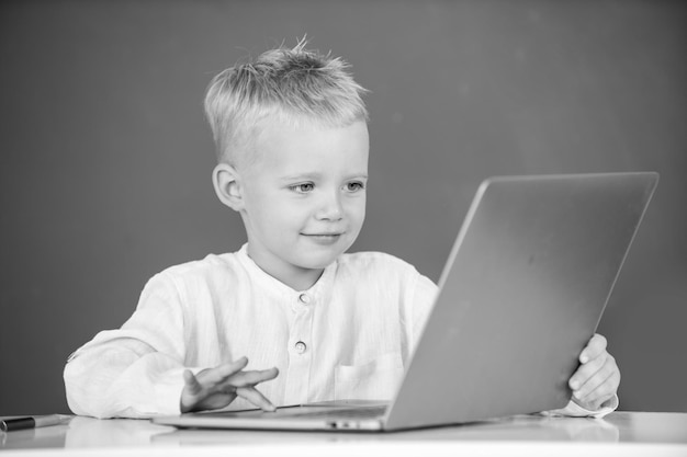 Chłopiec w szkole uczy się lekcji, siedząc przy biurku, studiując online e-learning, korzystaj z Internetu, Geniusz, szkolenie komputerowe dla dzieci w zakresie programowania