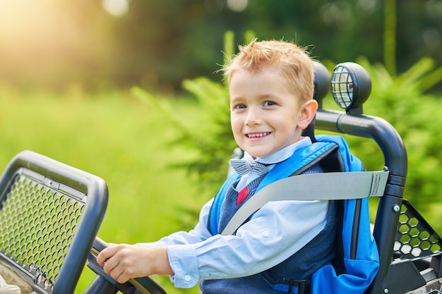chłopiec w wieku szkolnym prowadzący samochód dla dzieci z plecakiem