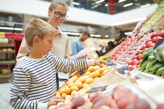 Chłopiec wybiera owoce w supermarkecie