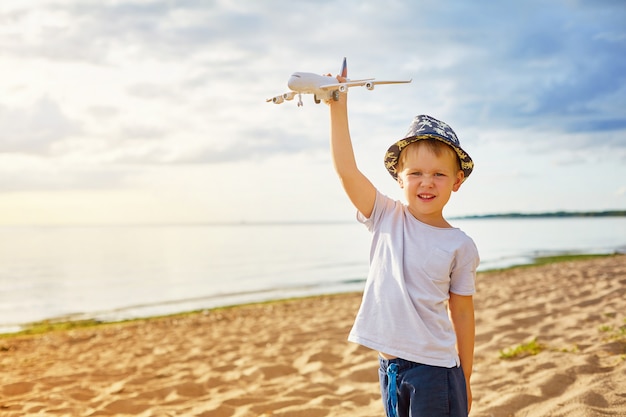 Chłopiec Z Samolotem W Jego Rękach Na Plaży