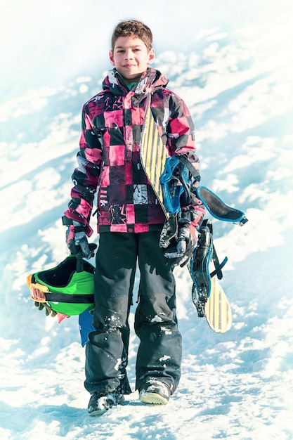 Chłopiec z snowboardem w górskim kurorcie zimowym