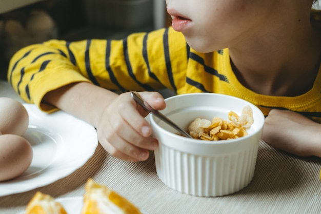 Chłopiec zjada rano śniadanie ze zbóż z mlekiem. płatki z bliska
