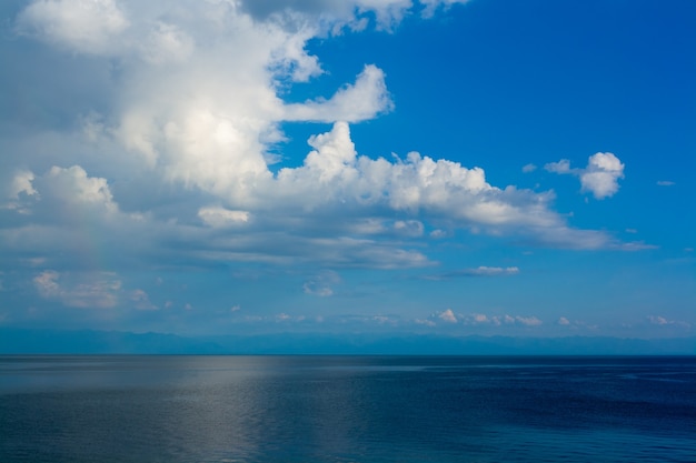 Chmury Cumulus na tle błękitnego nieba nad jeziorem Bajkał. Obraz poziomy.
