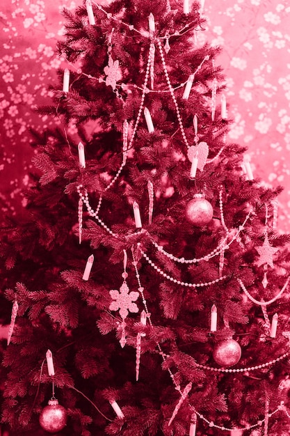 Choinka bożonarodzeniowa i noworoczna udekorowana w stylu vintage retro czerwona fioletowa jodła lub świerk zimowy sezon wakacyjny w domu stonowana w modnym kolorze roku 2023 viva magenta