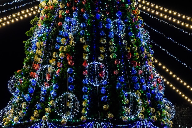 Choinka i bożonarodzeniowe lampki na tle czarnego nocnego nieba