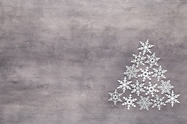 Choinka wykonana z białych płatków śniegu na szarym tle z pustym miejscem na tekst. Nowy rok i pocztówka świąteczna.