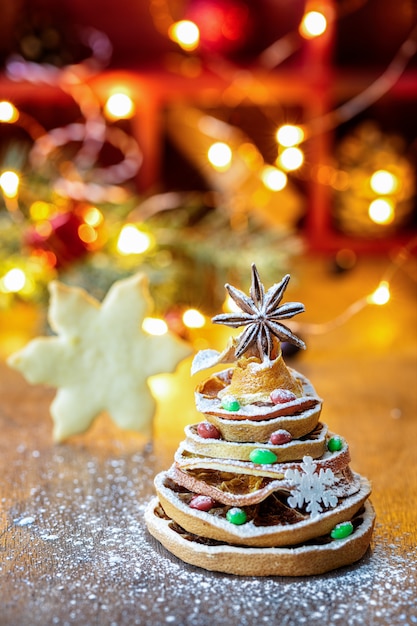 Choinka wykonana z suszonych plasterków pomarańczy i gwiazdki anyżu, ze świątecznym światłem i ciasteczkiem