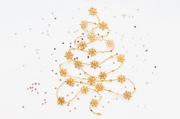 Choinka wykonana ze złotej śnieżynki ze srebrnymi konfetti gwiazd.