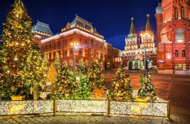 Choinki na Placu Maneżowym w Moskwie w pobliżu Bramy Zmartwychwstania i ozdoby choinkowe w nocnym oświetleniu