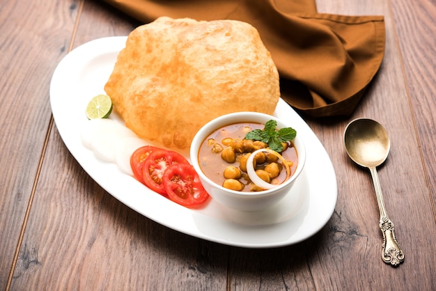 Chole Bhature lub curry z ciecierzycy i smażone puri podawane w naczyniach z terakoty na białym tle. selektywne skupienie