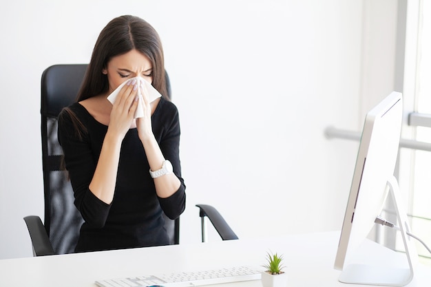 Chora kobieta biznesu cierpiąca w pracy za biurkiem w swoim biurze i mająca problem z alergią