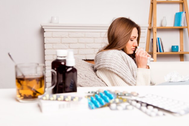 Zdjęcie chora kobieta, filiżanka herbaty, tabletki i mikstura