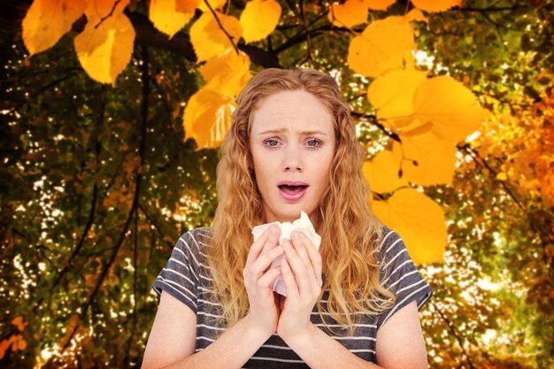 Zdjęcie chora kobieta kichająca w chusteczkę na jesiennych liściach na rośliny