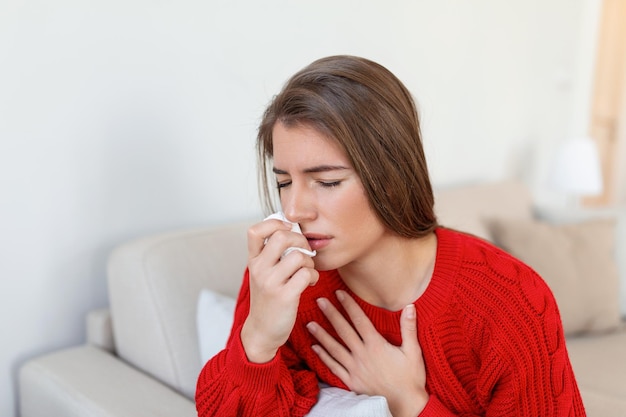Chora kobieta siada na łóżku czuje się niezdrowo dmuchając z nosa chora młoda kobieta cierpiąca na nieżyt nosa wącha mającą infekcję dróg oddechowych zachoruje na grypę potrzebuje leków