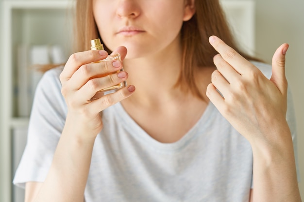 Chora kobieta wąchająca perfumy w butelce ma jeden z możliwych objawów zakażenia koronawirusem