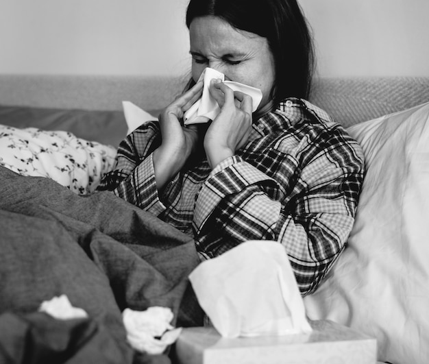 Zdjęcie chory kobieta kichanie w łóżku