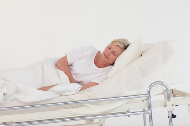 Chory starszy kobiety lying on the beach na łóżku szpitalnym