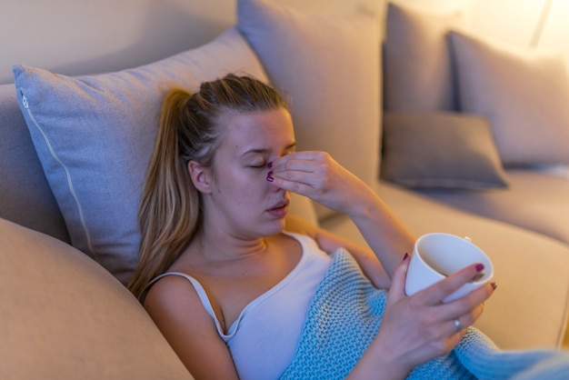 Chory Woman.Flu.Woman Caught Cold. Siedząc na kanapie. Bół głowy. Wirus