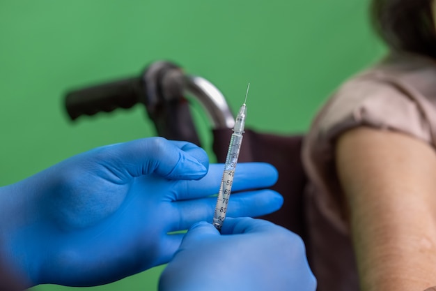 Zdjęcie chroma key, pielęgniarka robi zastrzyk szczepionki starszej kobiecie.