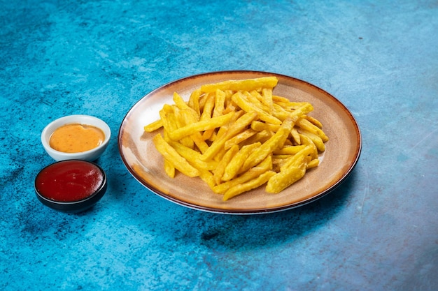 Chrupiące frytki lub chipsy ziemniaczane z dipem majonezowym i sosem pomidorowym podawane w widoku z boku talerza