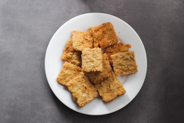 Chrupiące smażone tempeh na białym talerzu z szarym tłem