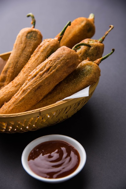 Chrupiące zielone Chilli Pakora lub Mirchi Bajji, podawane z ketchupem na nastrojowym tle. Jest to popularna przekąska na herbatę z Indii, szczególnie w Monsoon. Selektywne skupienie